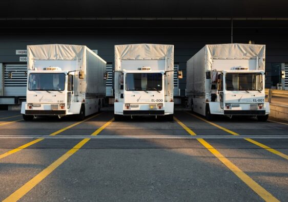 Drei weiße Elektro-Nutzfahrzeuge an einer Laderampe