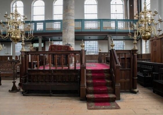 Historischer Synagogeninnenraum mit erhöhter Bima und rotem Teppich